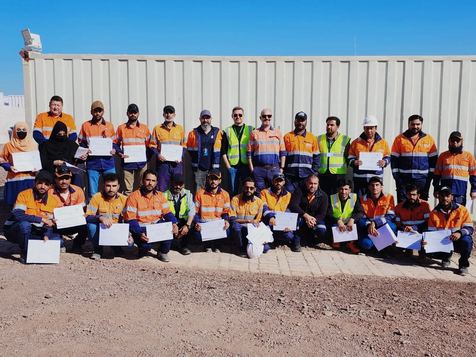 Participants in high-visibility workwear holding their training certificates
