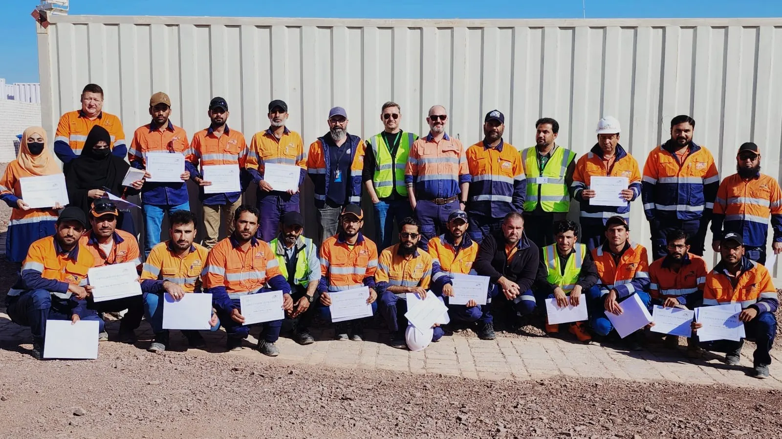 Participants in high-visibility workwear holding their training certificates